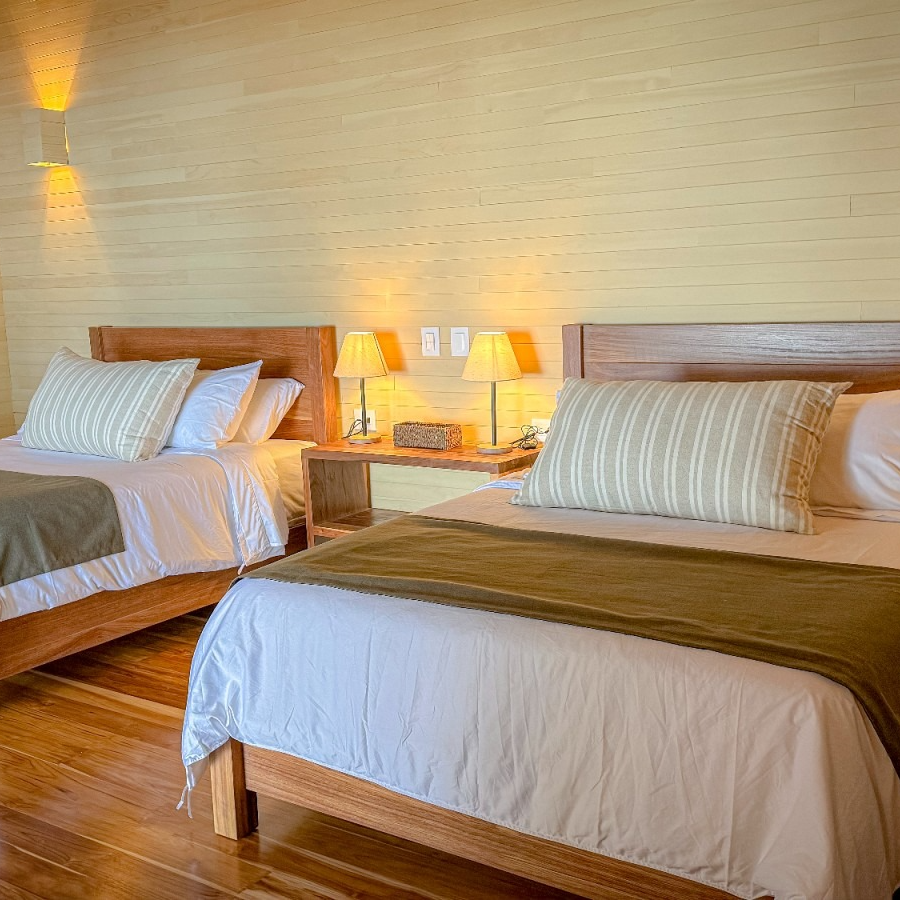 A hotel room with two beds , lamps and a wooden floor.