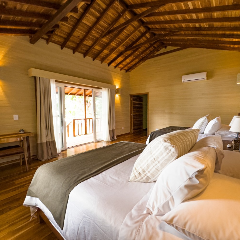 A bedroom with two beds , a desk and a sliding glass door.
