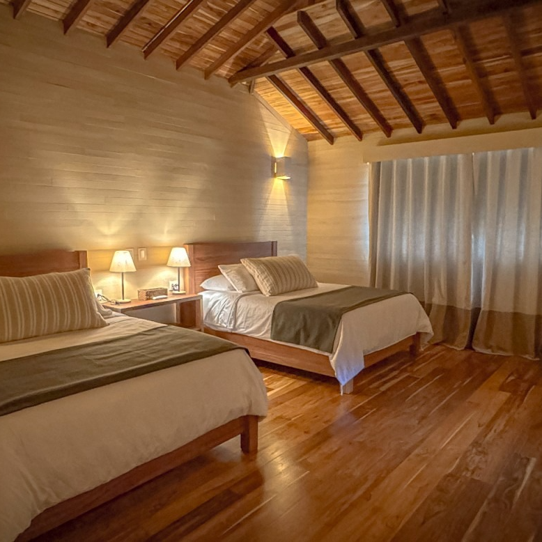 A hotel room with two beds and a wooden floor.