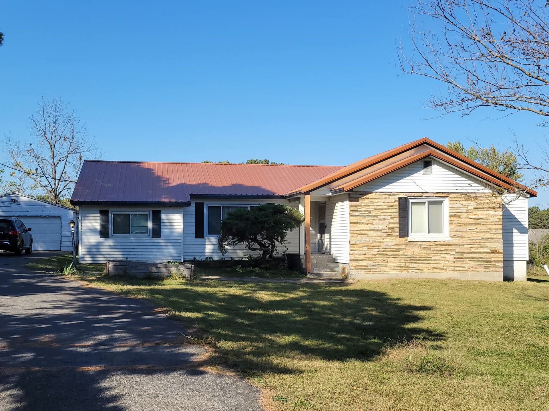 A one-story house with a white and tan exterior under a clear blue sky.