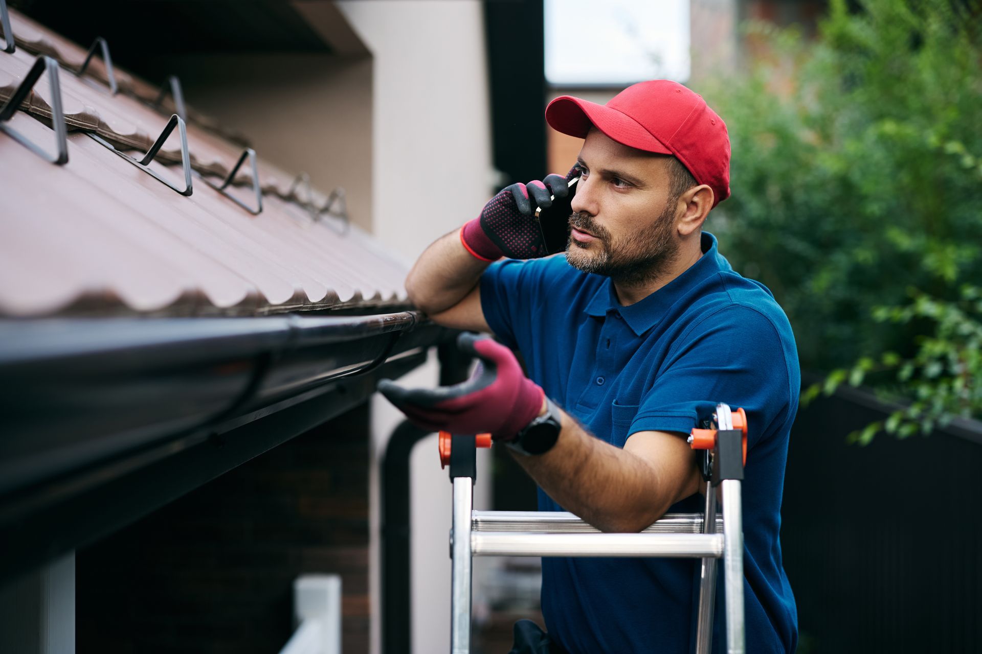 Roofing service contractor inspecting gutter on ladder