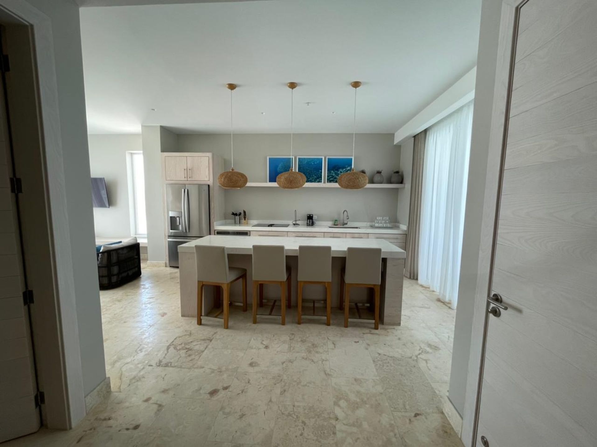 Modern open-plan kitchen and dining area with white cabinets, island, and six beige chairs