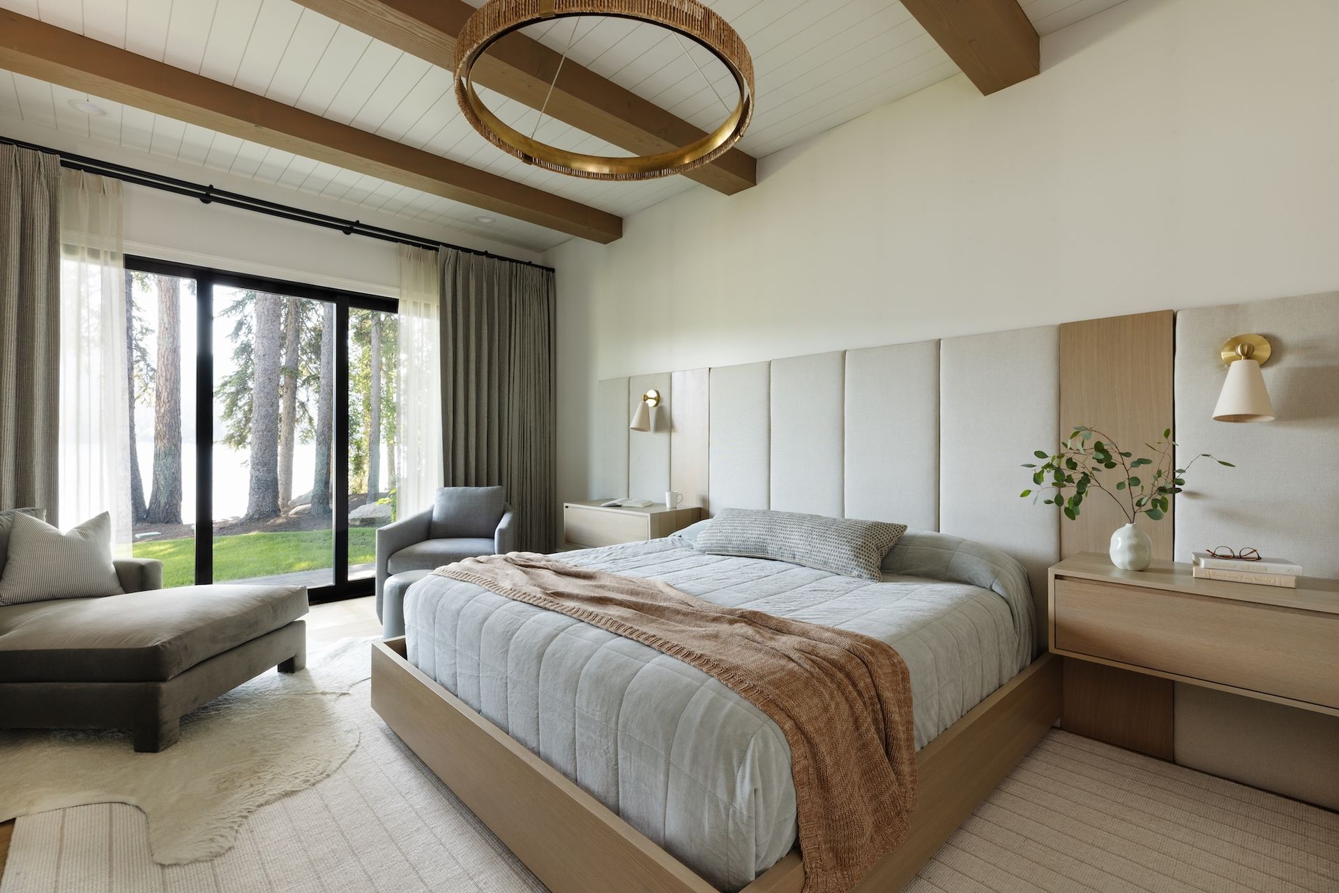 Bright modern bedroom with a king bed, large windows, and a bench near the sliding glass doors