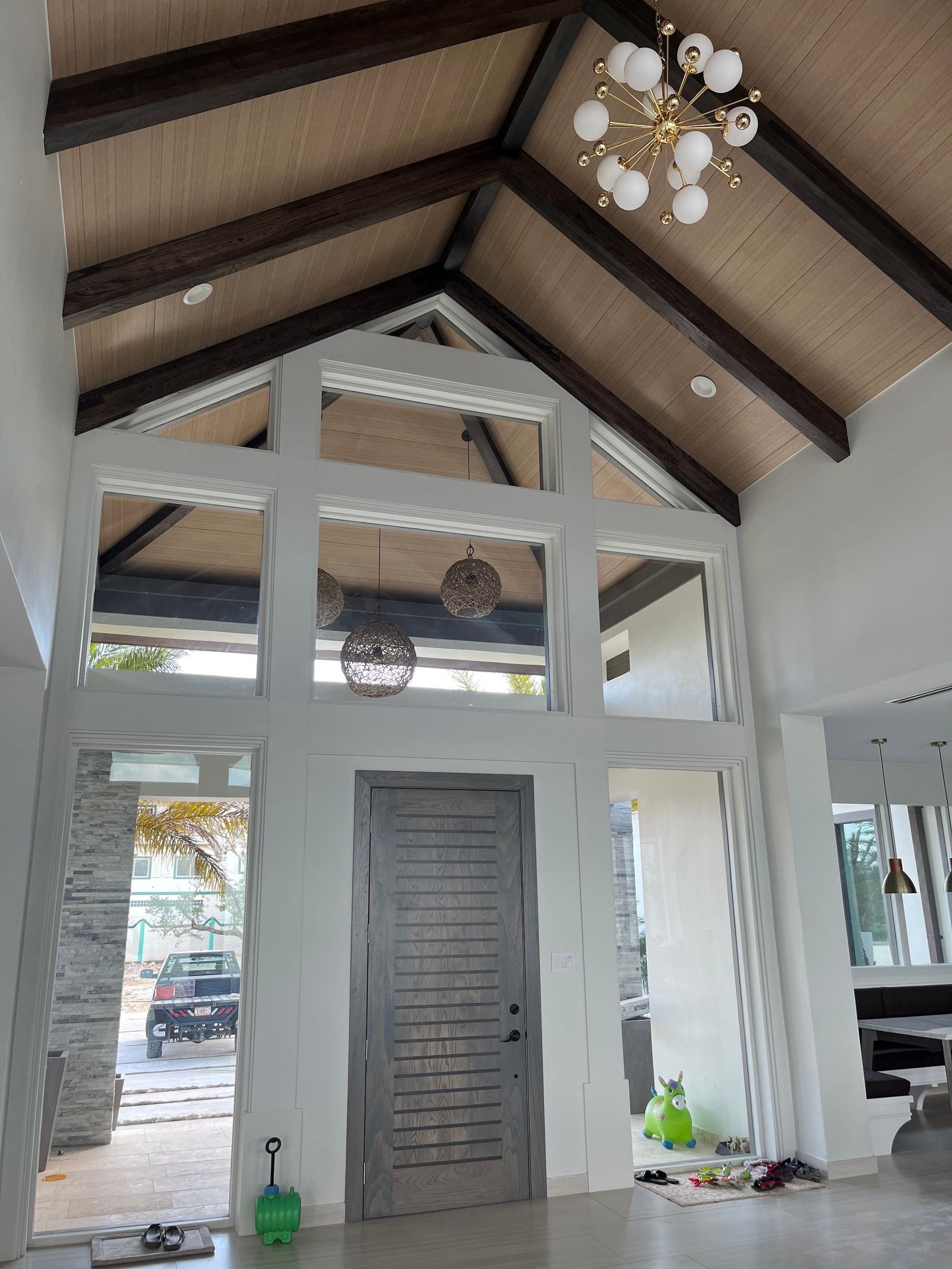 Interior of a bright chapel with a high wooden ceiling, white walls, and a central gray door.
