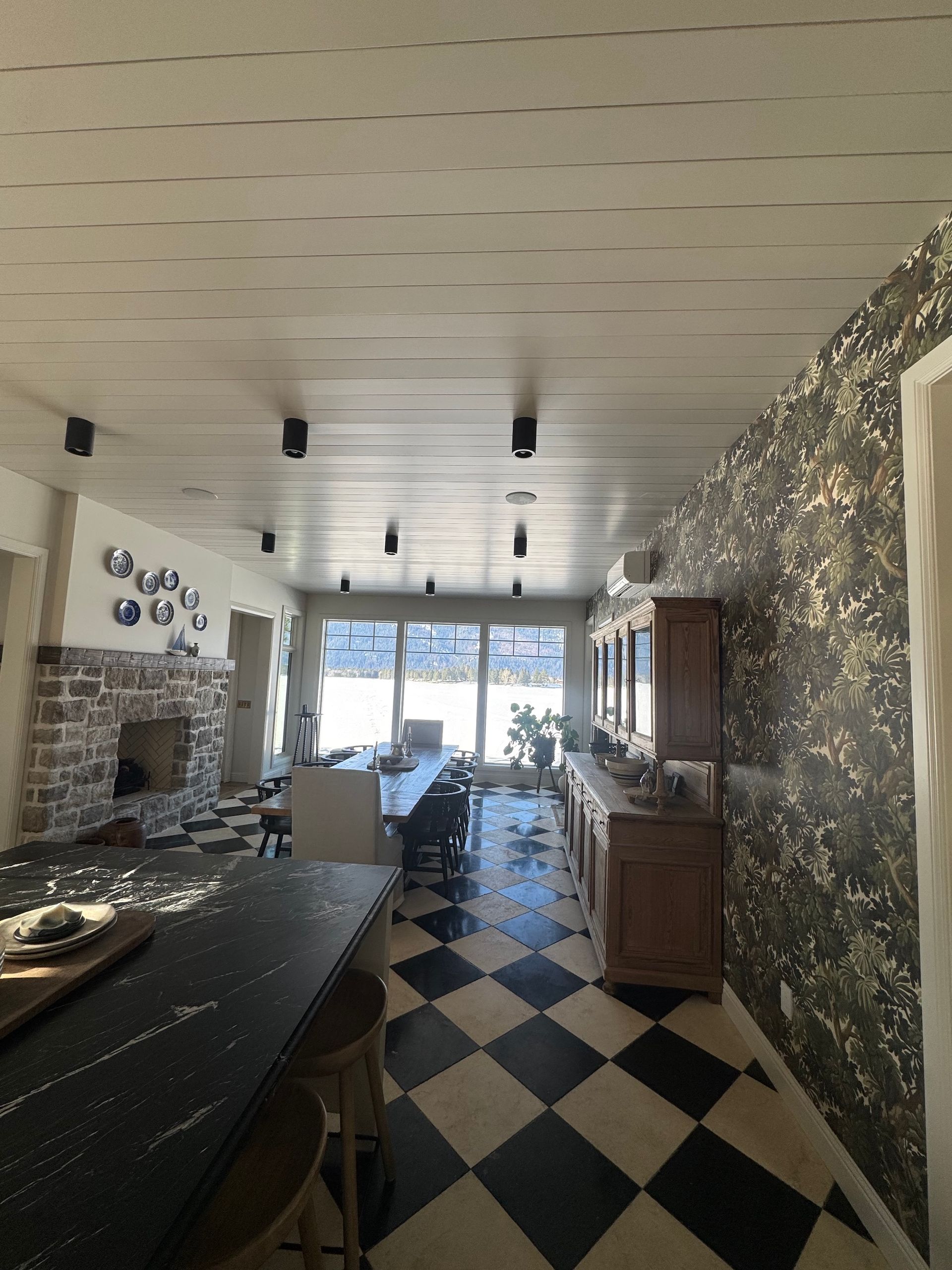 Long narrow kitchen with checkered floor, stone walls, and bright windows at the far end
