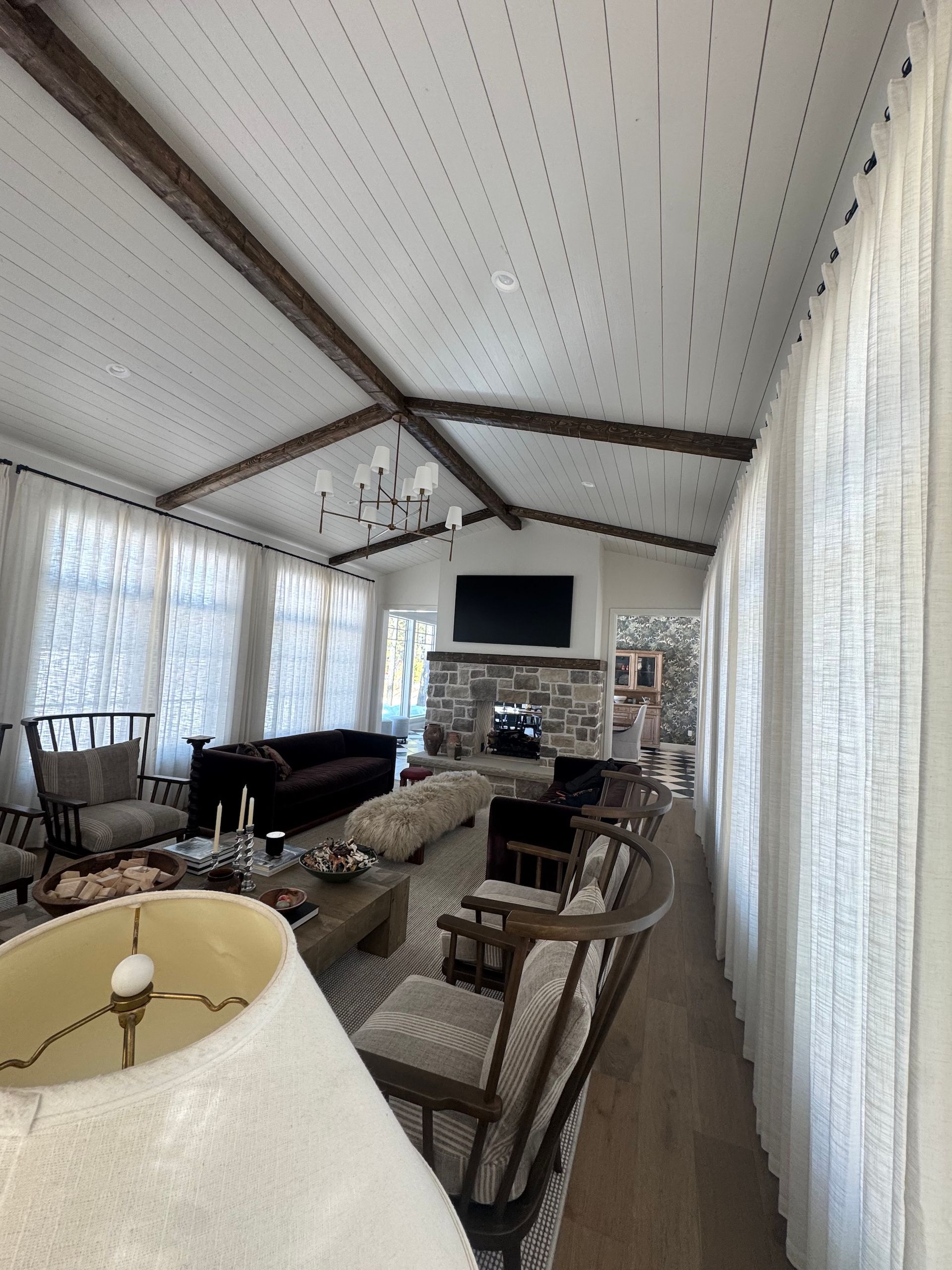 Sunroom with wicker chairs, patterned ceiling, sheer curtains, and a TV on the far wall