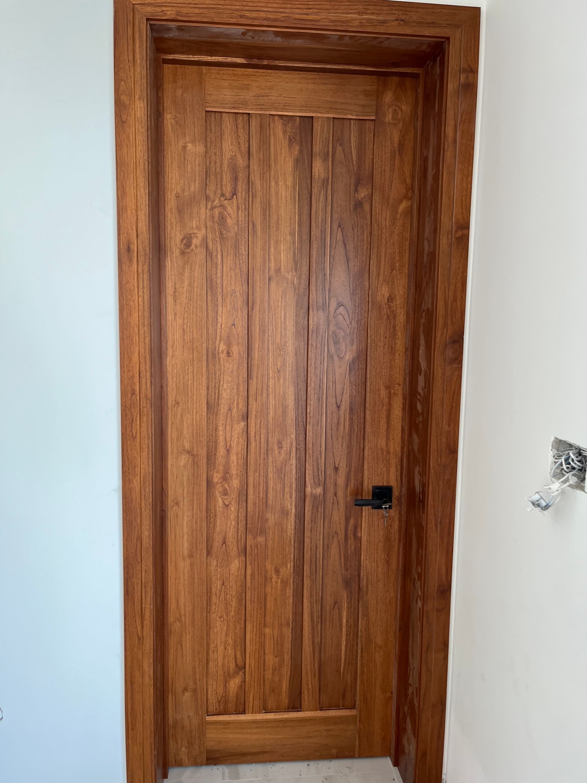 Wooden interior door with dark handle in a white wall