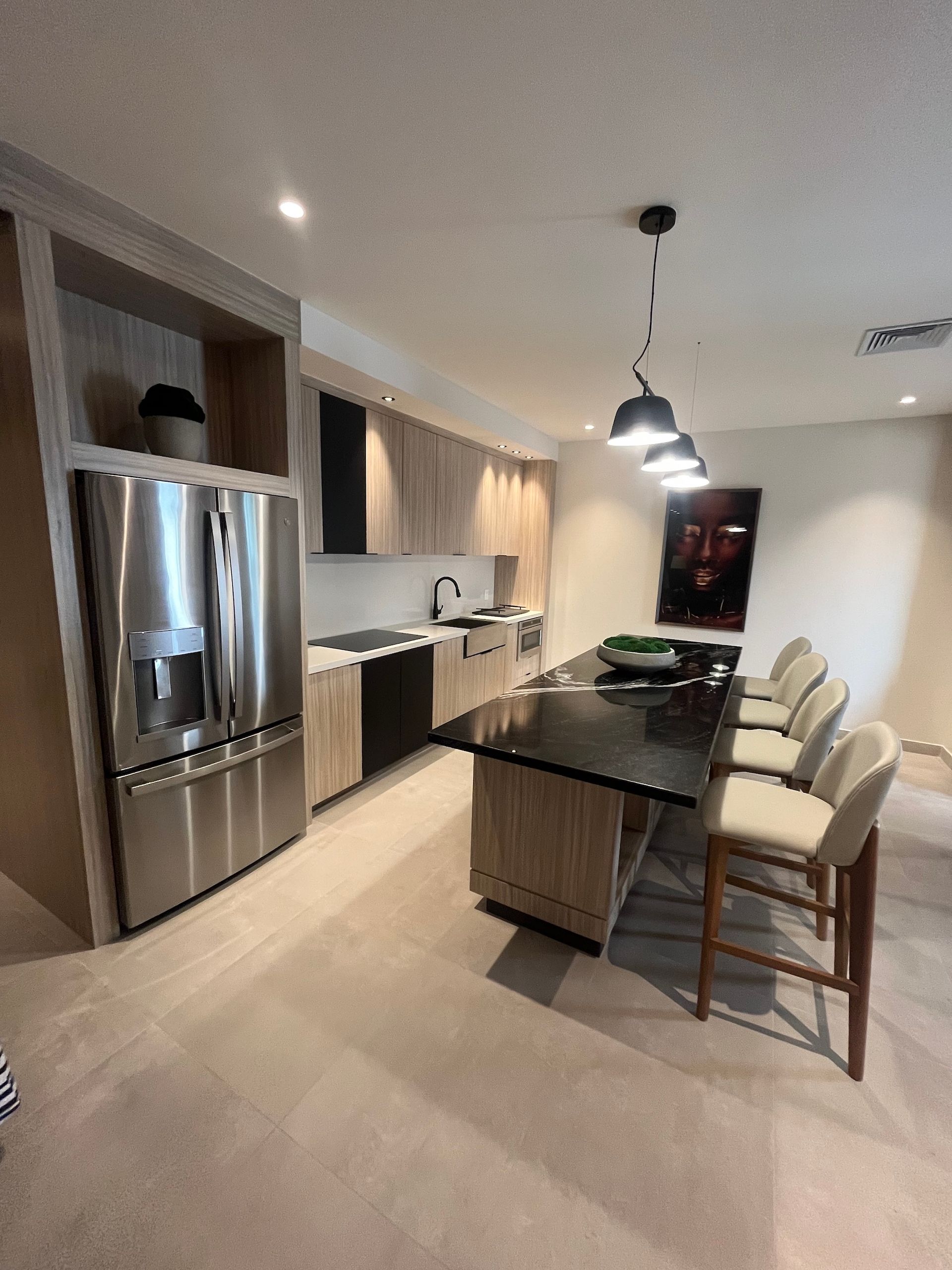Modern kitchen with stainless steel appliances, dark cabinets, island, and two bar stools