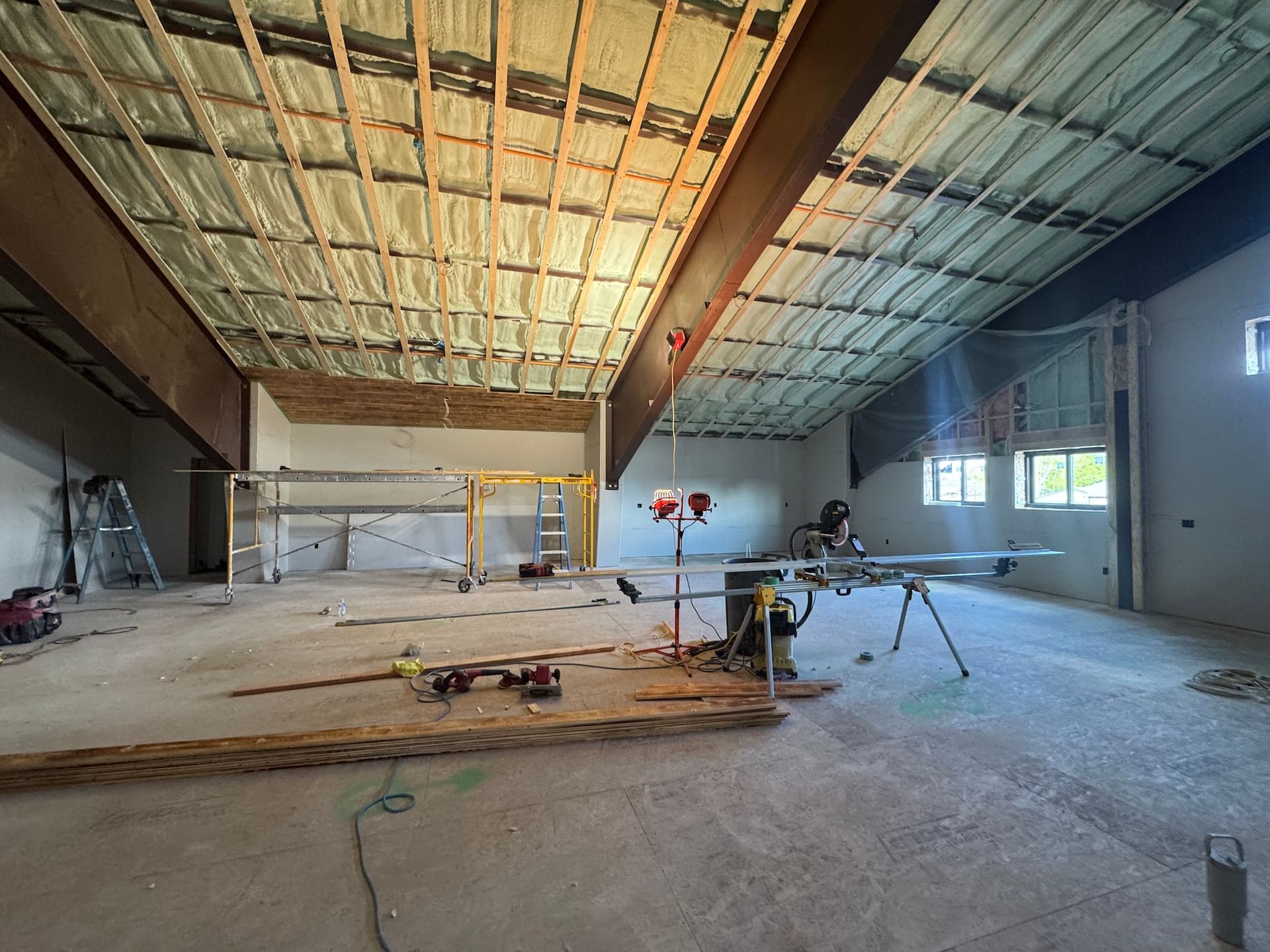 Empty unfinished industrial interior with exposed roof, concrete floor, and construction equipment