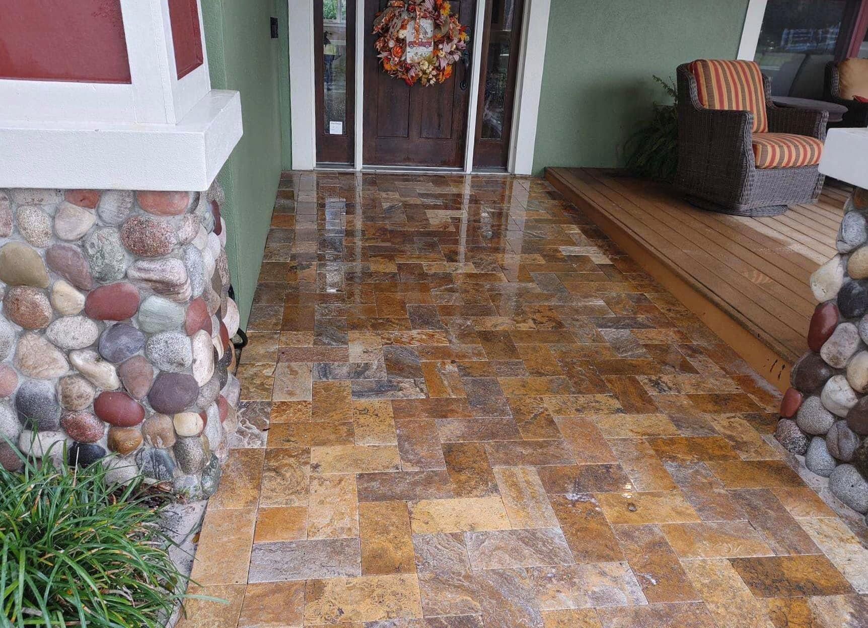 Stone-tiled front porch with rock columns and a wooden door entrance