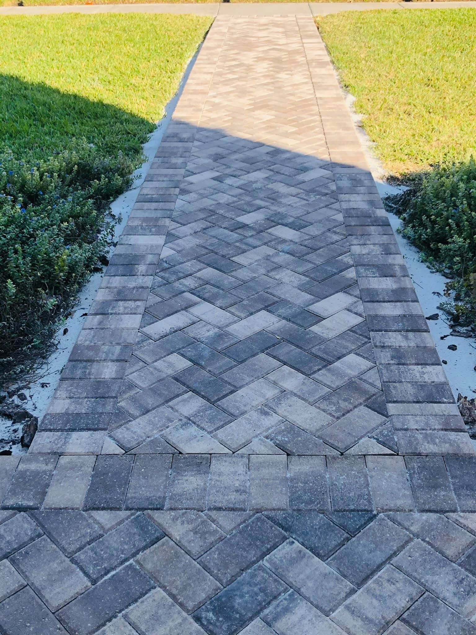 Brick walkway leading through green grass in a sunny outdoor yard