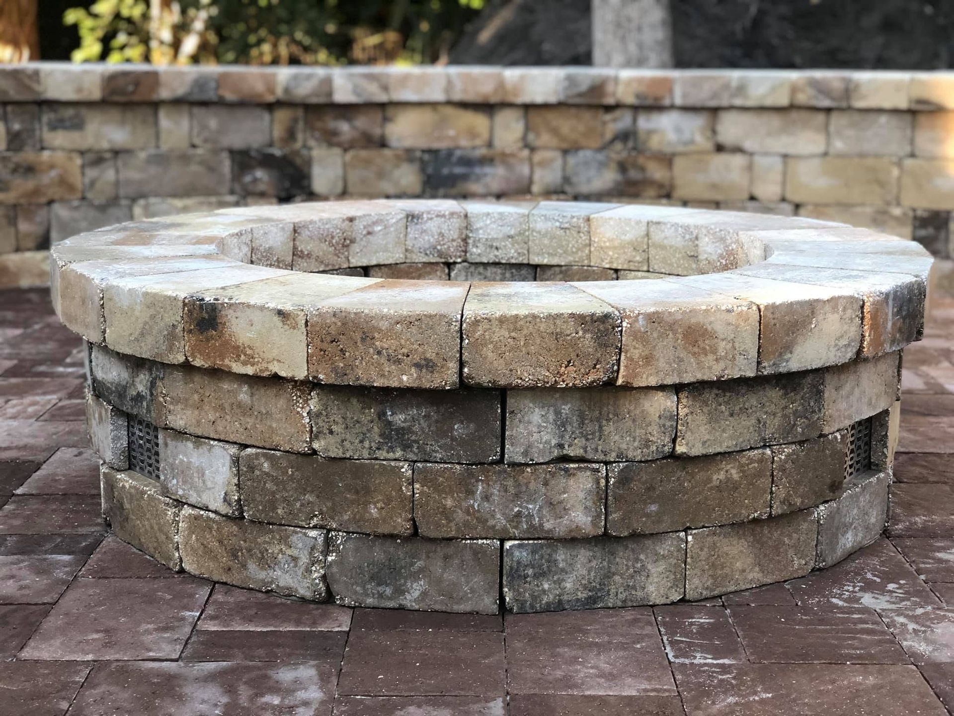 Stone outdoor fire pit surrounded by a low stacked-stone wall and brick patio
