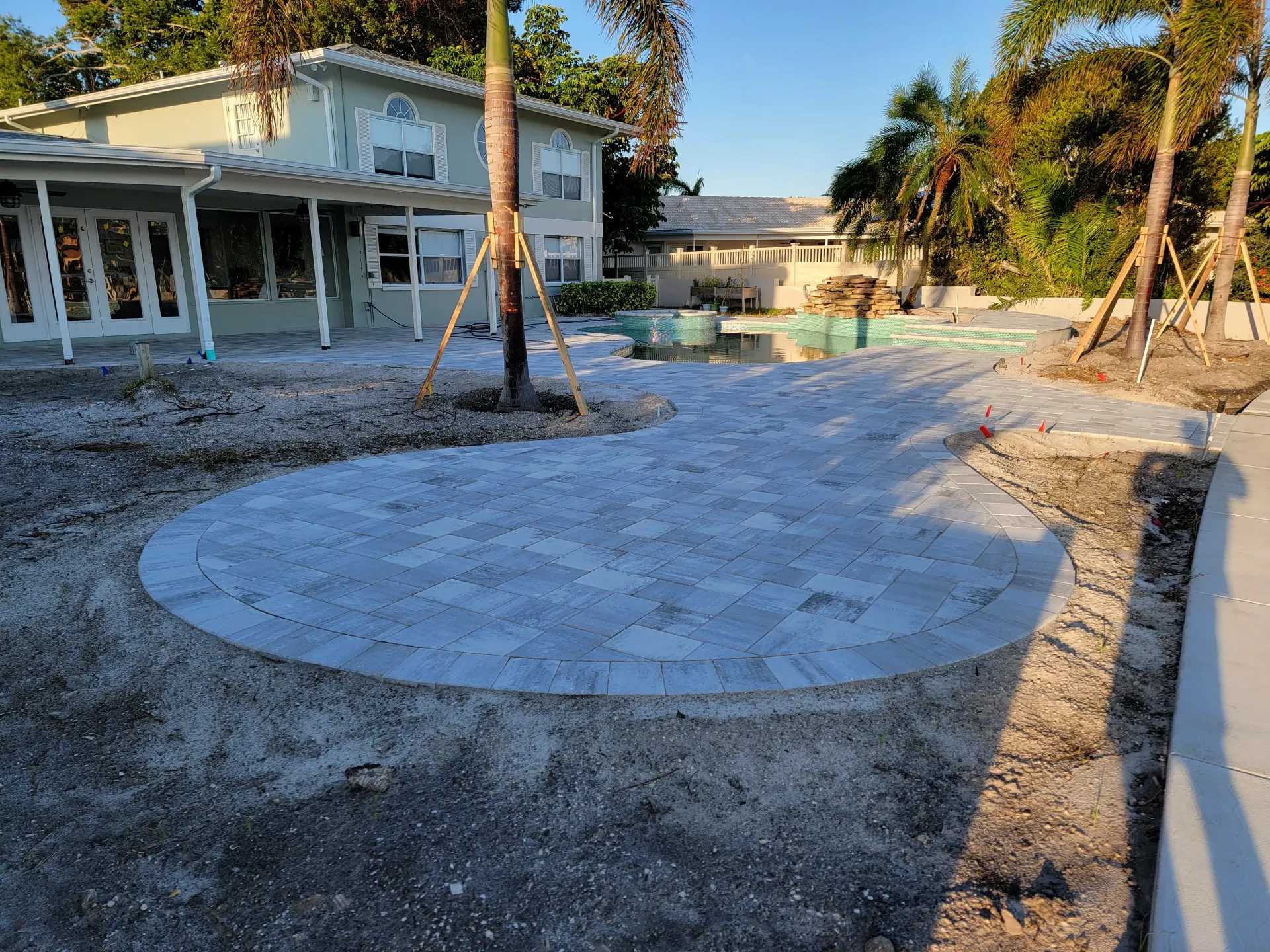 Concrete planter in Tampa, FL with palm trees beside a pool, casting shadows in bright sunlight