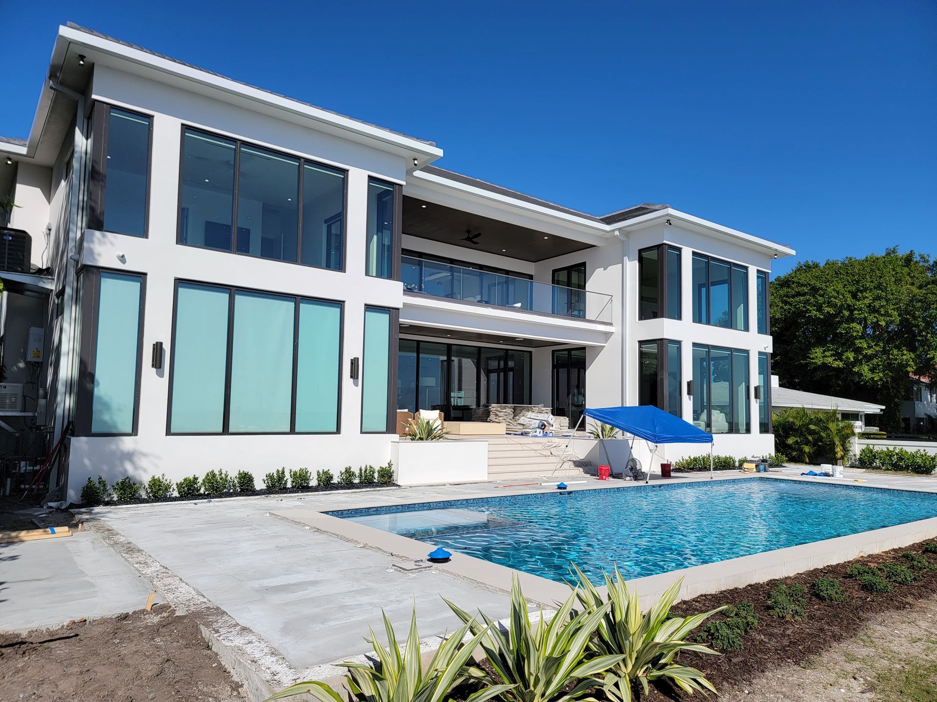 Modern two-story white house with large windows and a swimming pool in the foreground