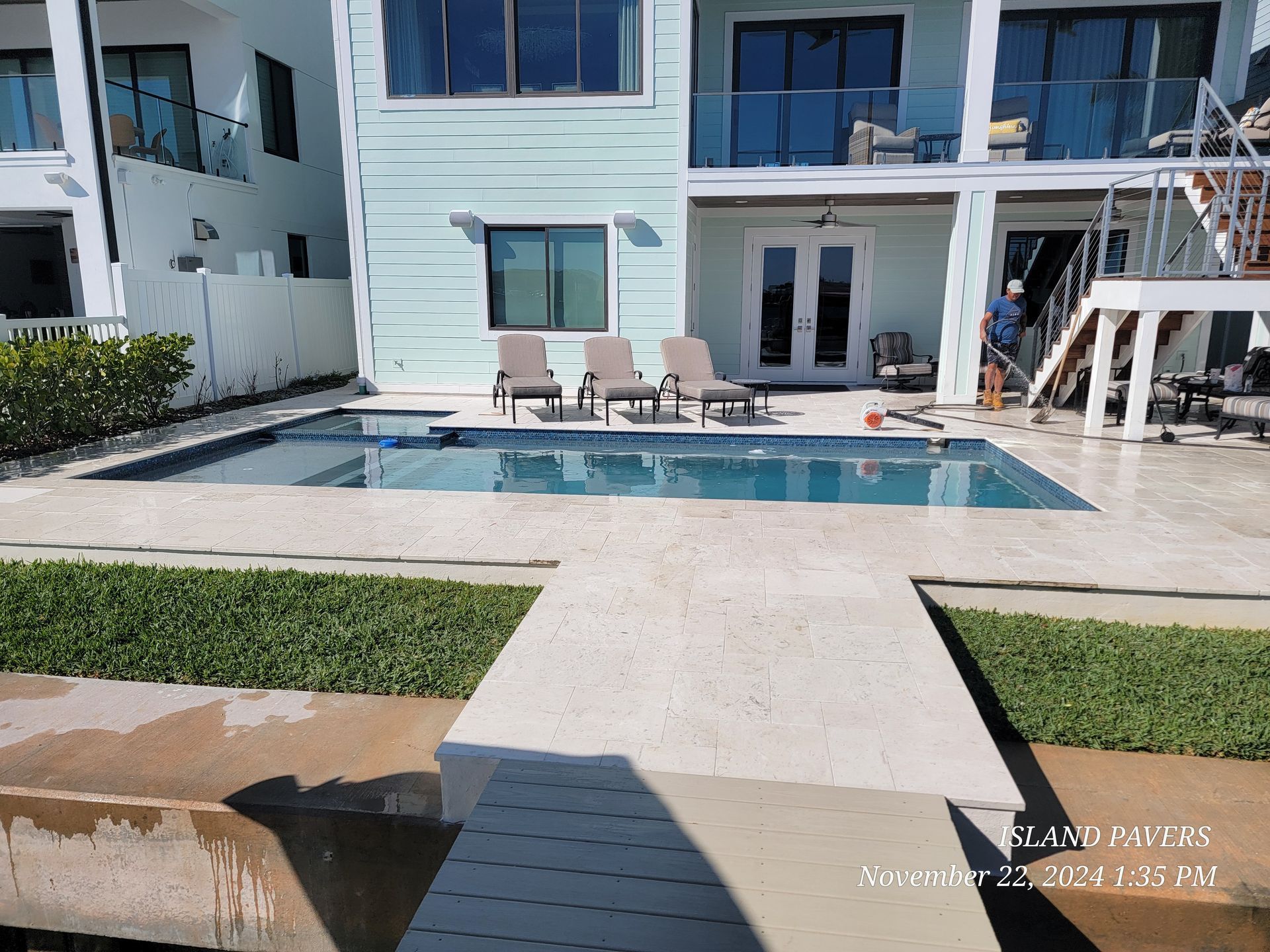 Modern marble pavers with a backyard swimming pool, patio seating, and manicured lawn in a Florida outdoor living space.
