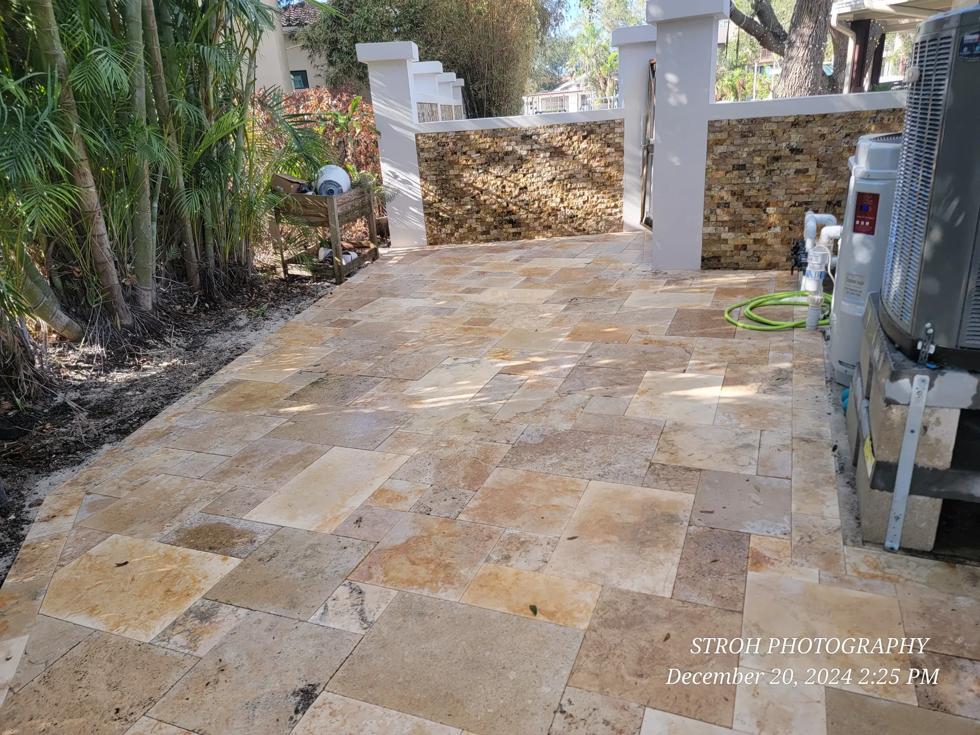 Stone fire pit on a paved patio beside a low stone retaining wall.