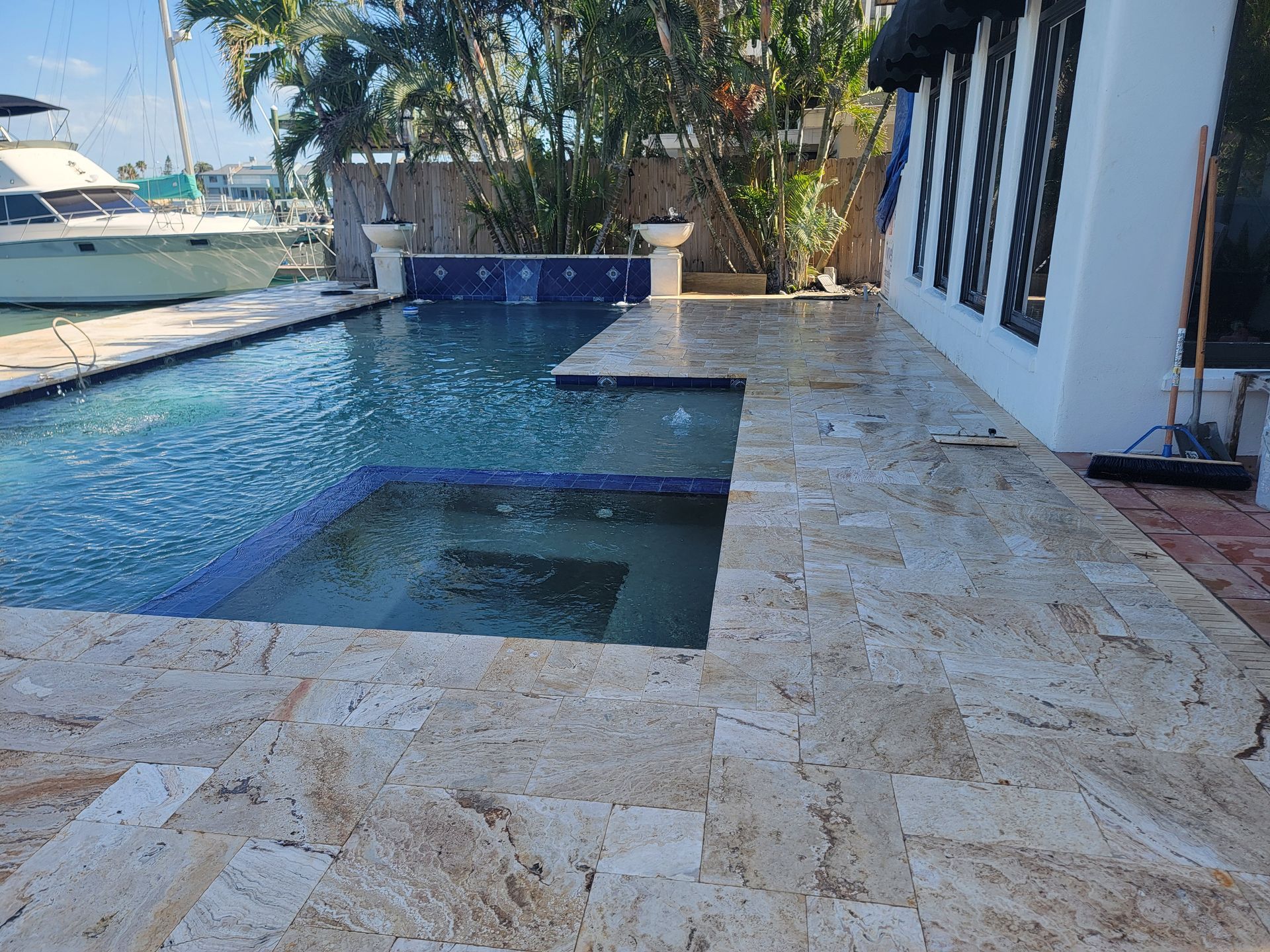 Poolside patio with a blue swimming pool, stone deck, and waterfront home in a Florida outdoor living space.