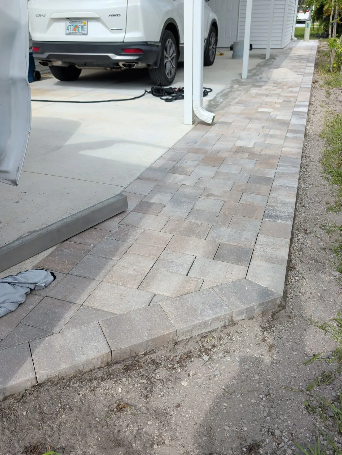 White paver stone block garden wall in front of a house with green lawn and tropical plants