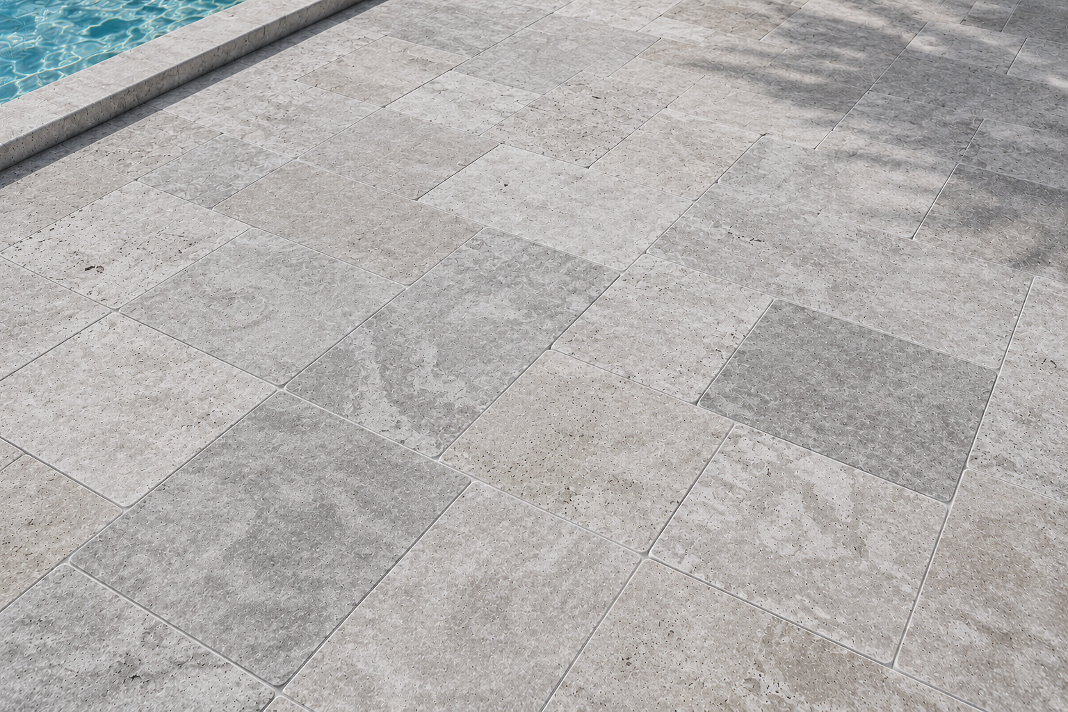 Gray marble tiled pavement beside a blue pool edge in Florida