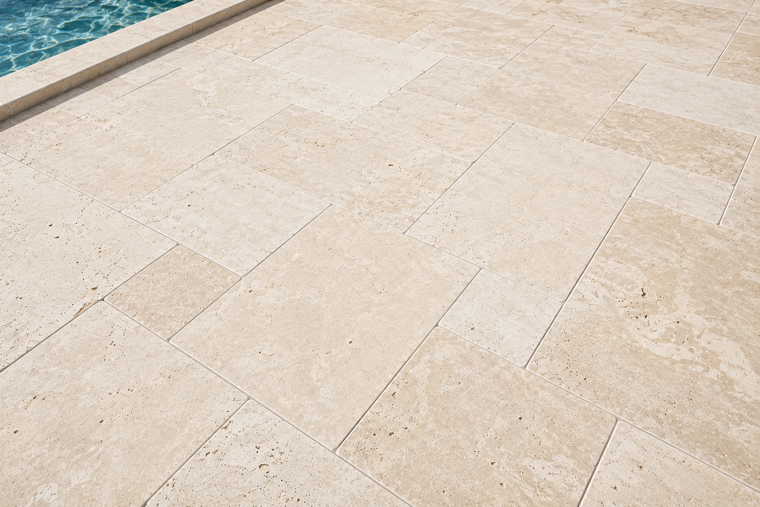 Light beige marble poolside patio beside blue water in florida