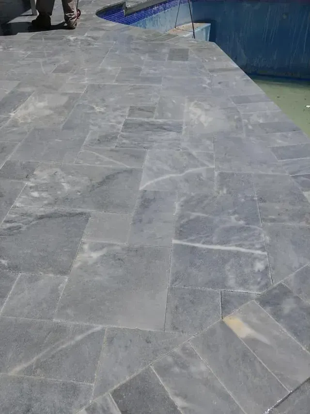 Gray marble walkway beside water, with a few people in the distance.