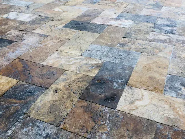 Mottled stone tile floor with mixed beige, gray, and brown rectangular tiles