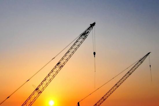 Two cranes with the sunset in the background
