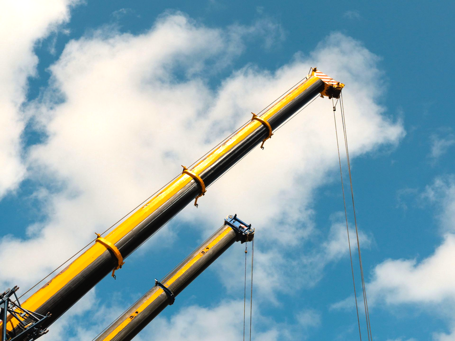 The top of a few cranes with the blue sky in the background.
