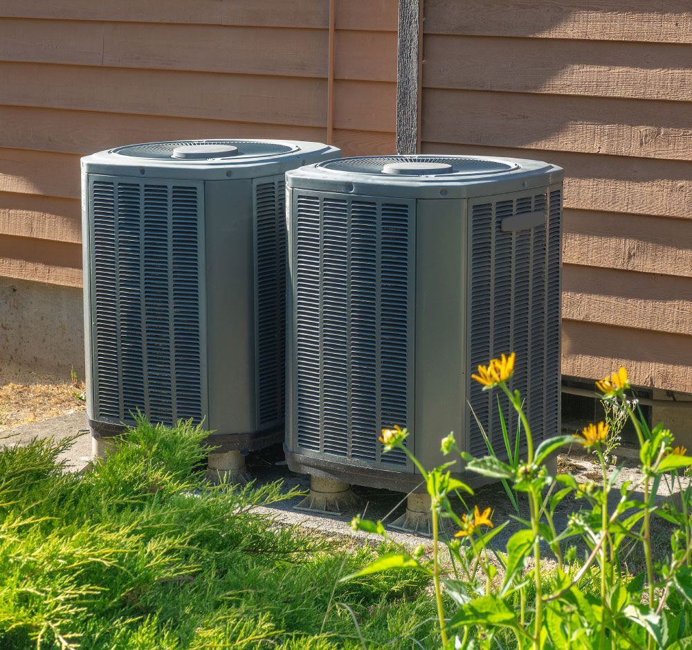 Two Air Conditioners are Next to Each Other on the Side of a House — Knoxville, TN — Compass Heating & Air Conditioning Inc. Two Air Conditioners are Next to Each Other on the Side of a House — Knoxville, TN — Compass Heating & Air Conditioning Inc.