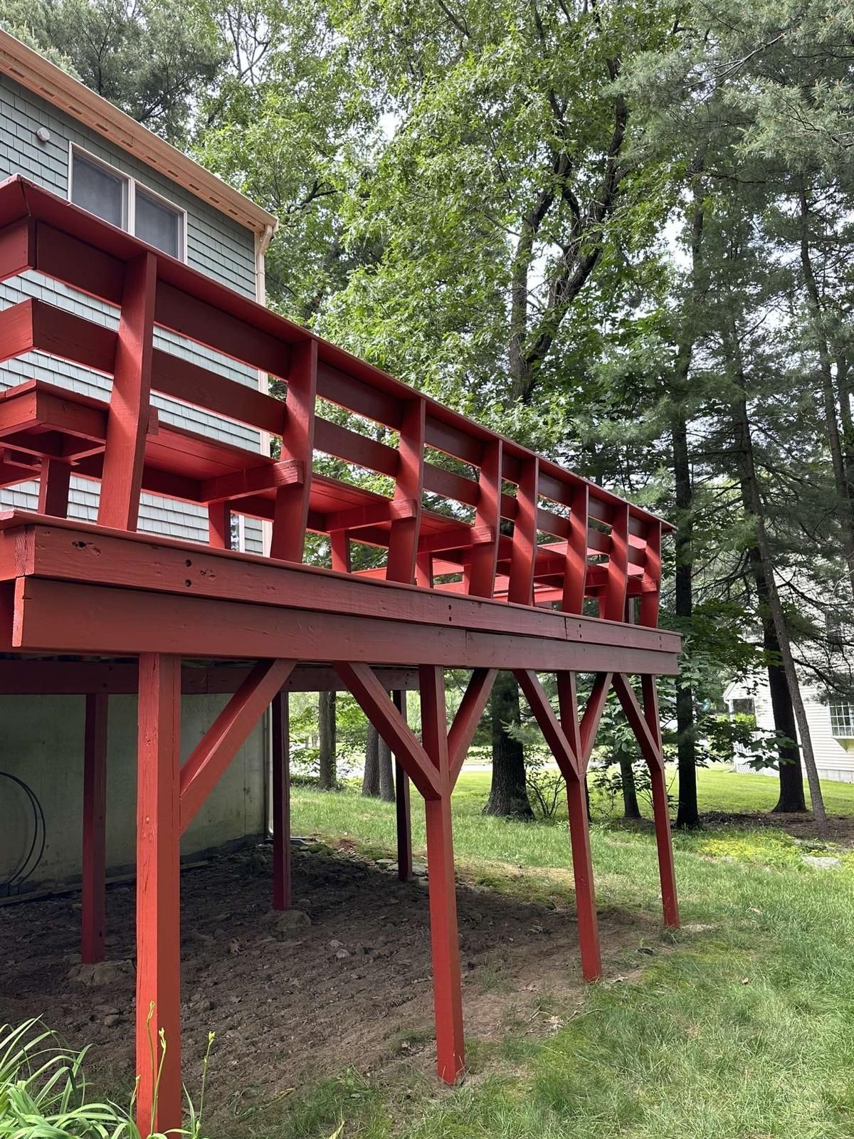 A red deck is sitting on top of a house surrounded by trees.