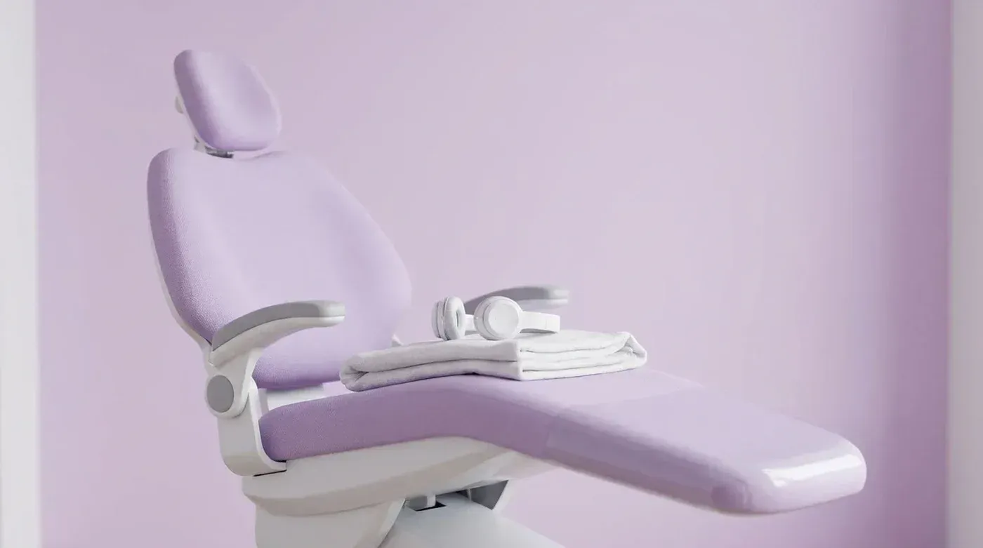 An empty lilac dental chair with a soft blanket and headphones, ready for a relaxed sedation visit