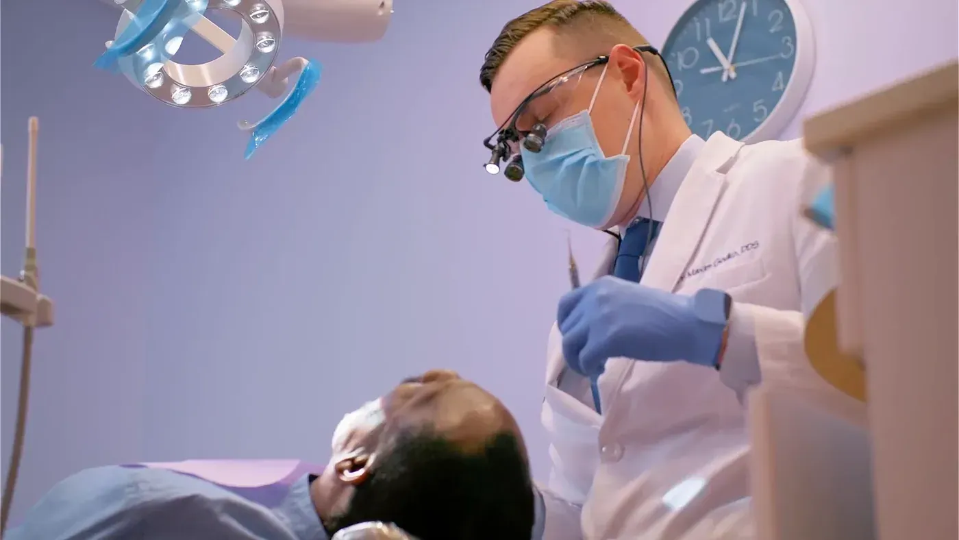 Dr. Maxim Godko treating a reclined patient to build worn teeth back with dental bonding