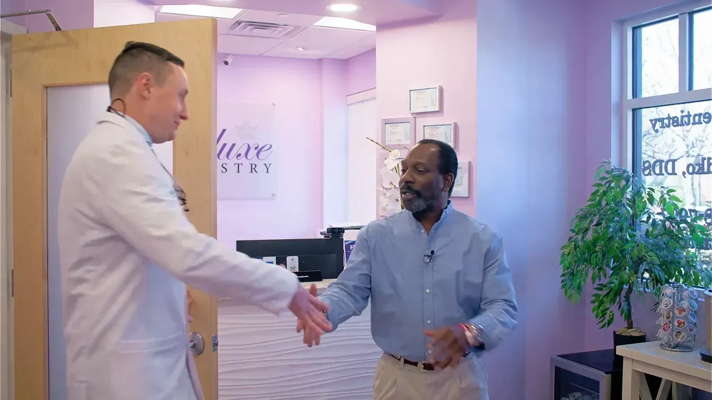 Doctor shaking hands with a patient at the front desk after an implant bridge consultation