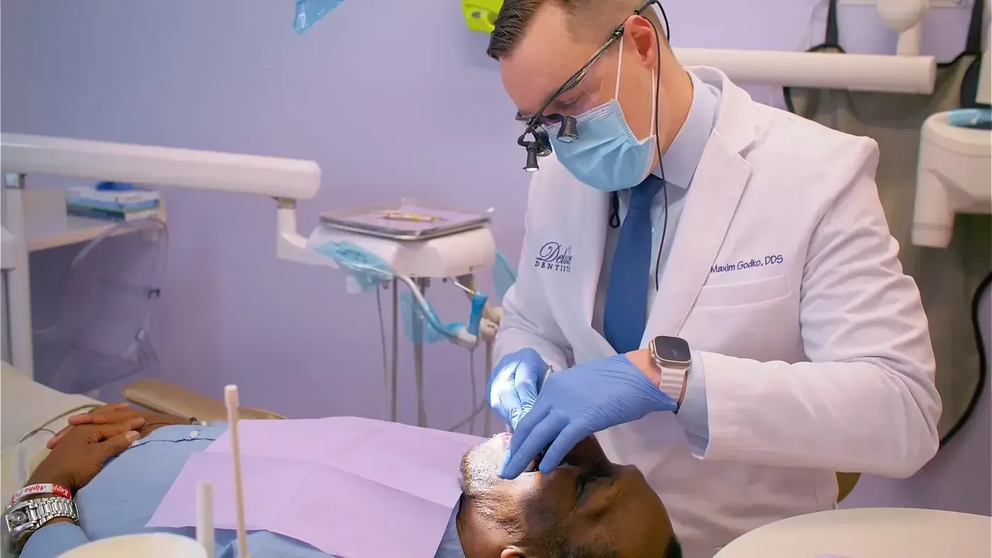 Dr. Maxim Godko examining a patient’s teeth and bite to compare Invisalign and braces