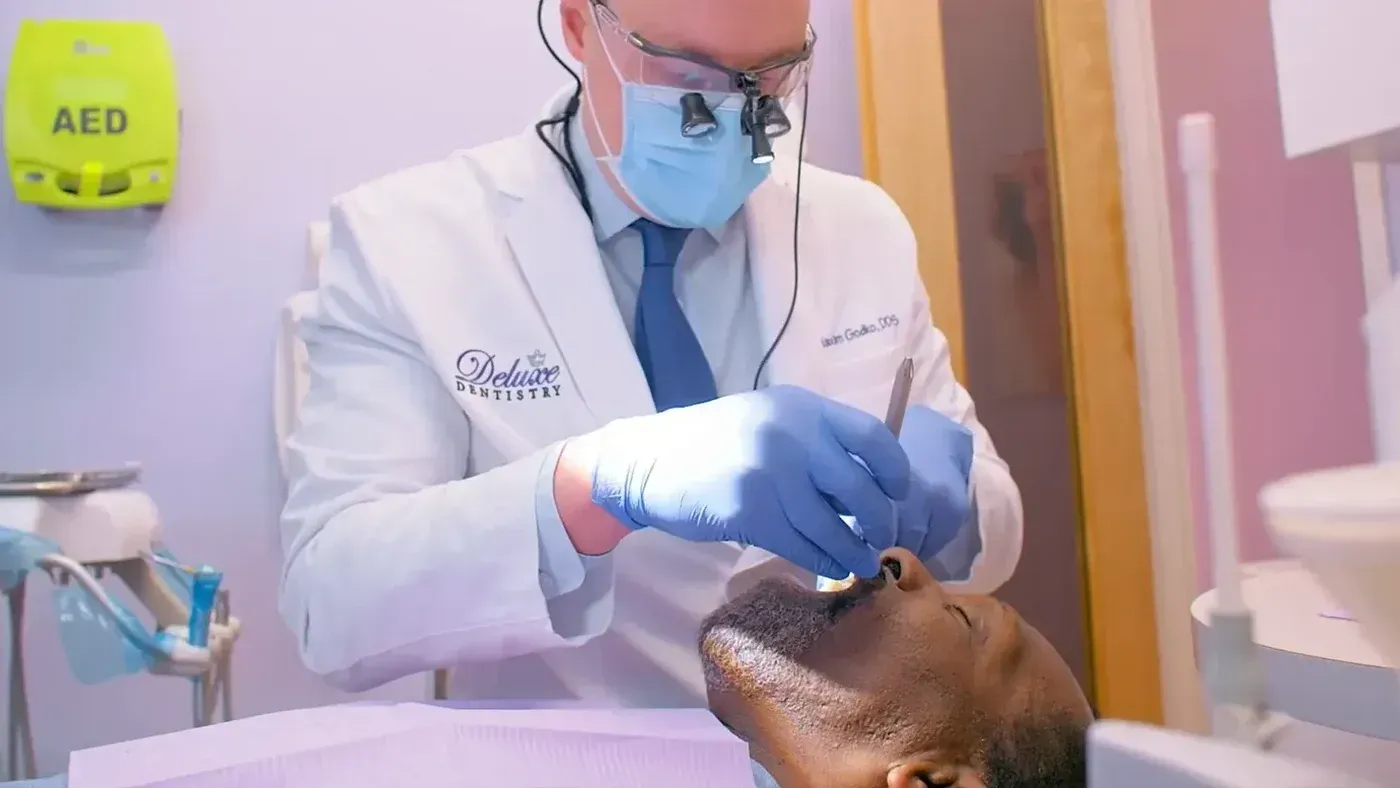 Dr. Maxim Godko in magnifying loupes restoring a patient’s tooth, the in-house work behind a dental crown