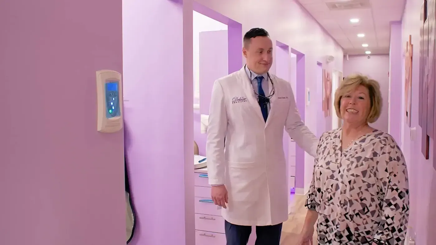 Smile Makeover: Dr. Godko with a smiling patient in the office hallway