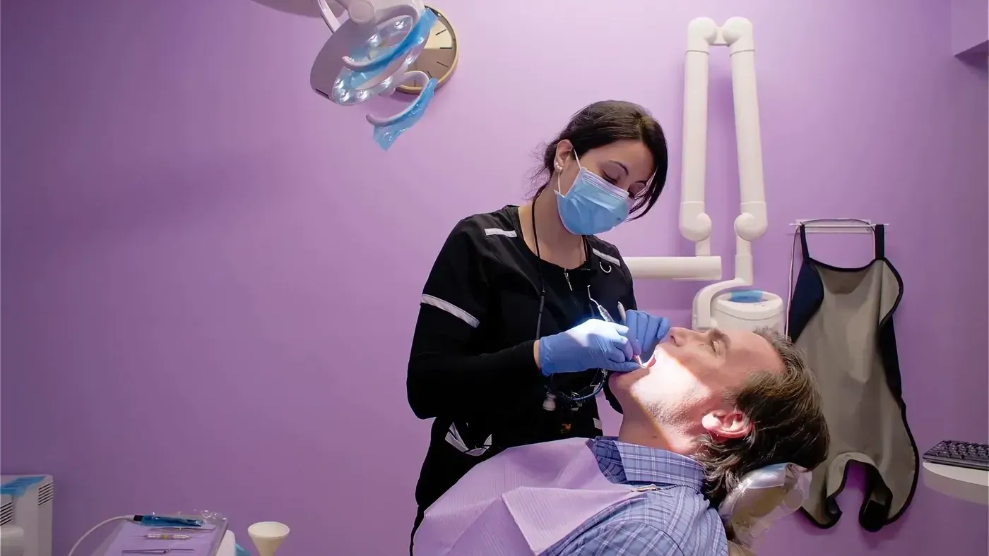 Hygienist cleaning a patient’s teeth so his gums are healthy before braces or Invisalign begin