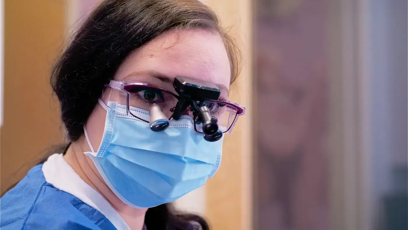 Periodontal Maintenance: hygienist wearing loupes and a mask