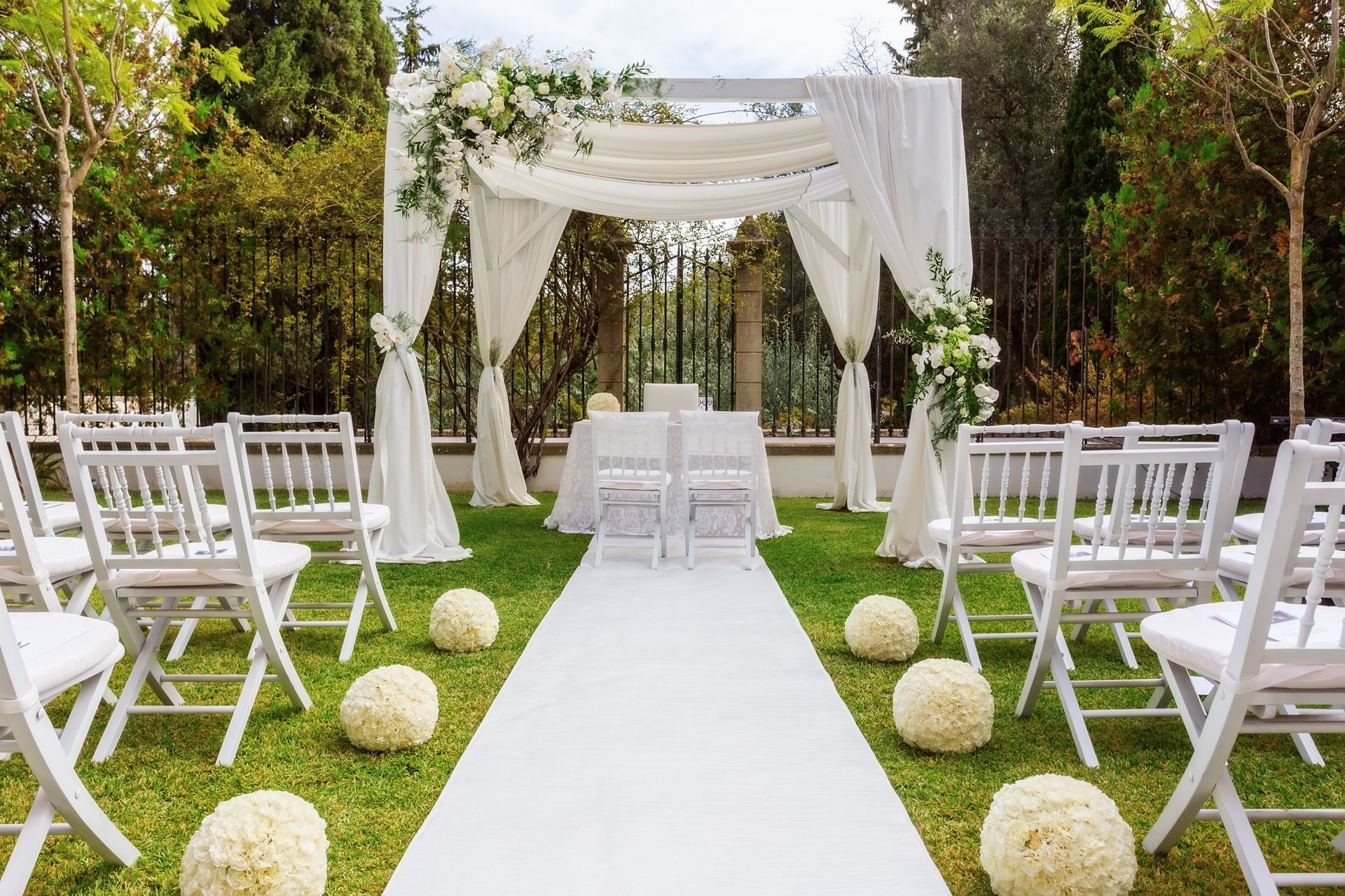 Elegant outdoor wedding reception with string lights, white-draped tables, and floral centerpieces at dusk