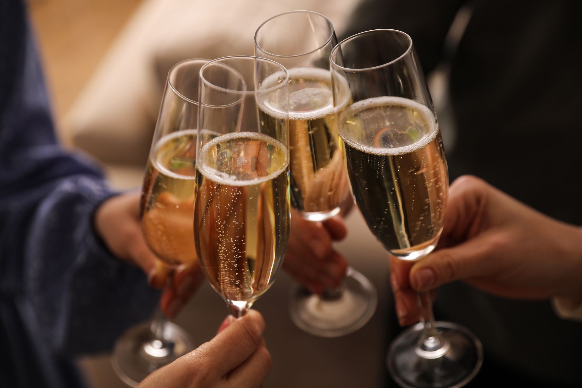 Hands clinking champagne flutes in a toast at a party