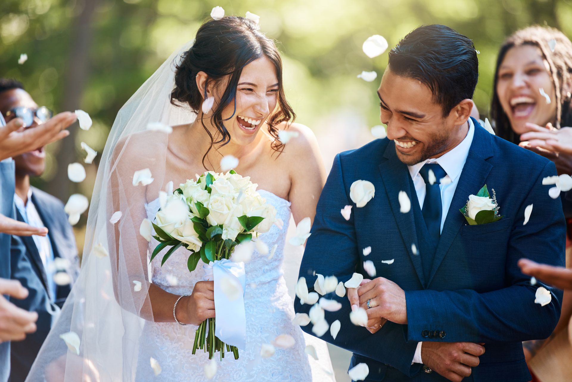 Newlyweds smiling and tossing flower petals outdoors after their wedding ceremony