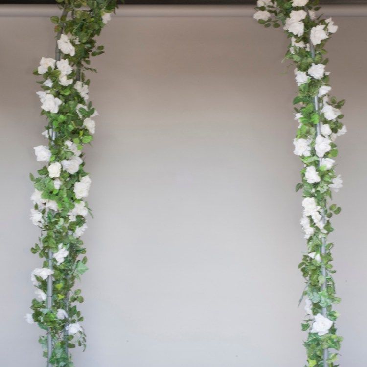 White floral and green vine archway framing a plain beige wall background