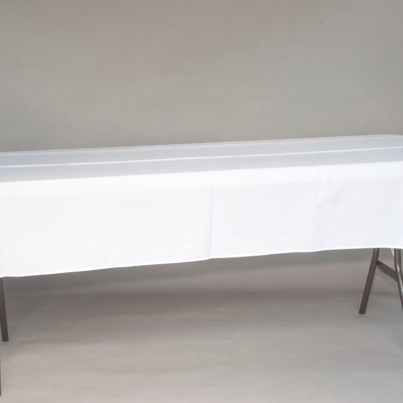 White table with a draped tablecloth against a plain beige wall in a simple room.