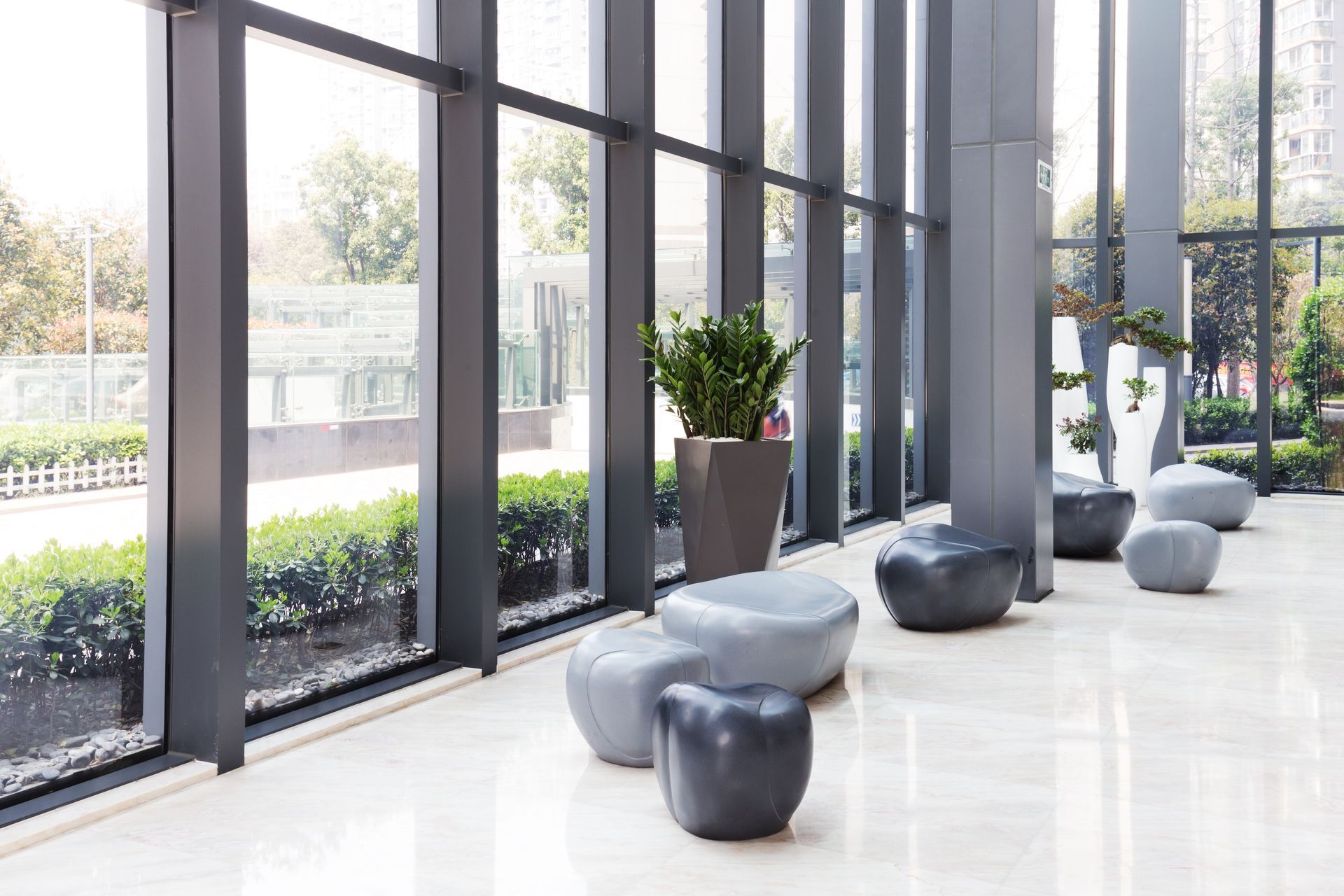 Modern building lobby with large floor-to-ceiling windows and pebble ottomans.