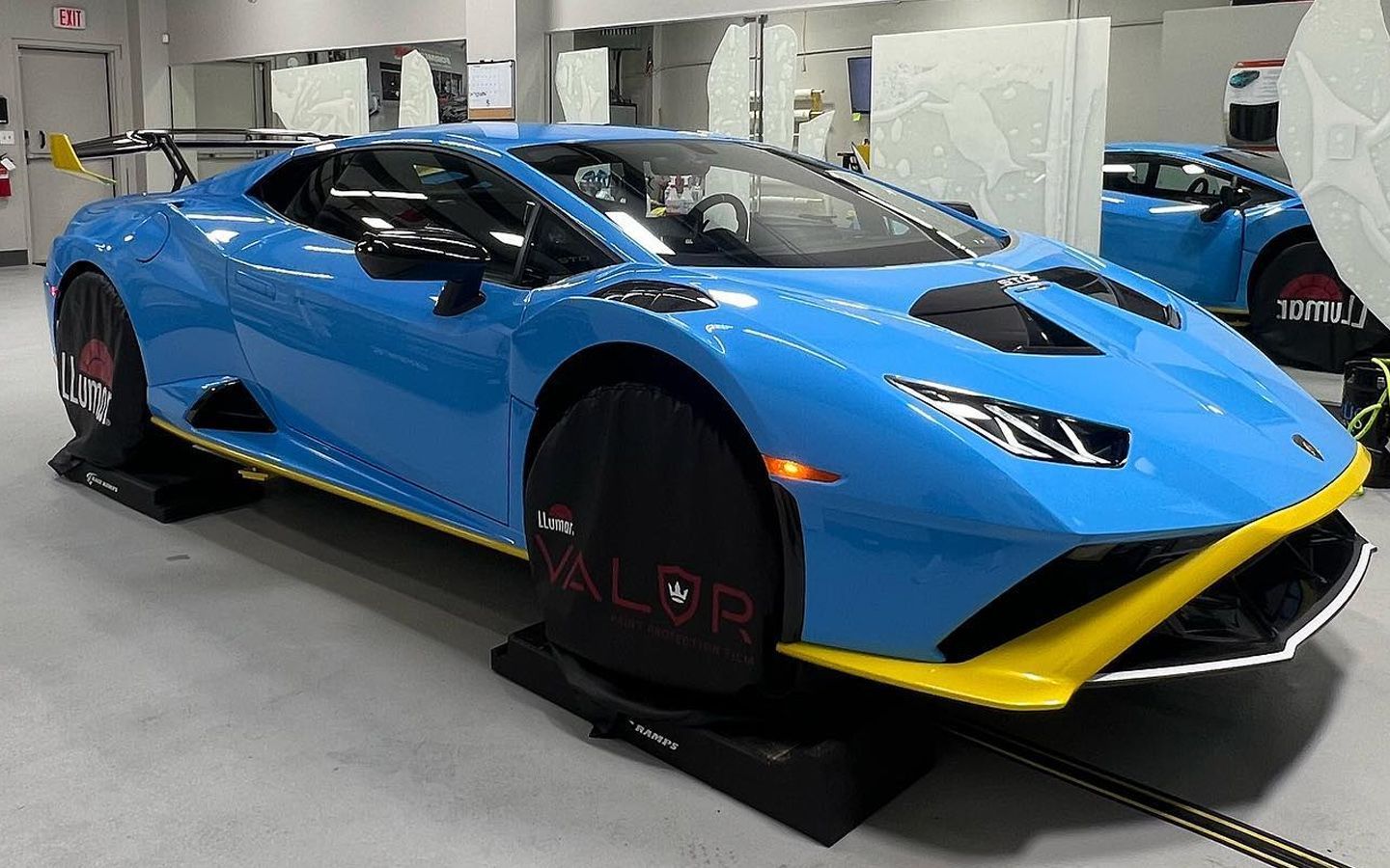 Blue Lamborghini Huracán STO with yellow accents in a detailing shop.