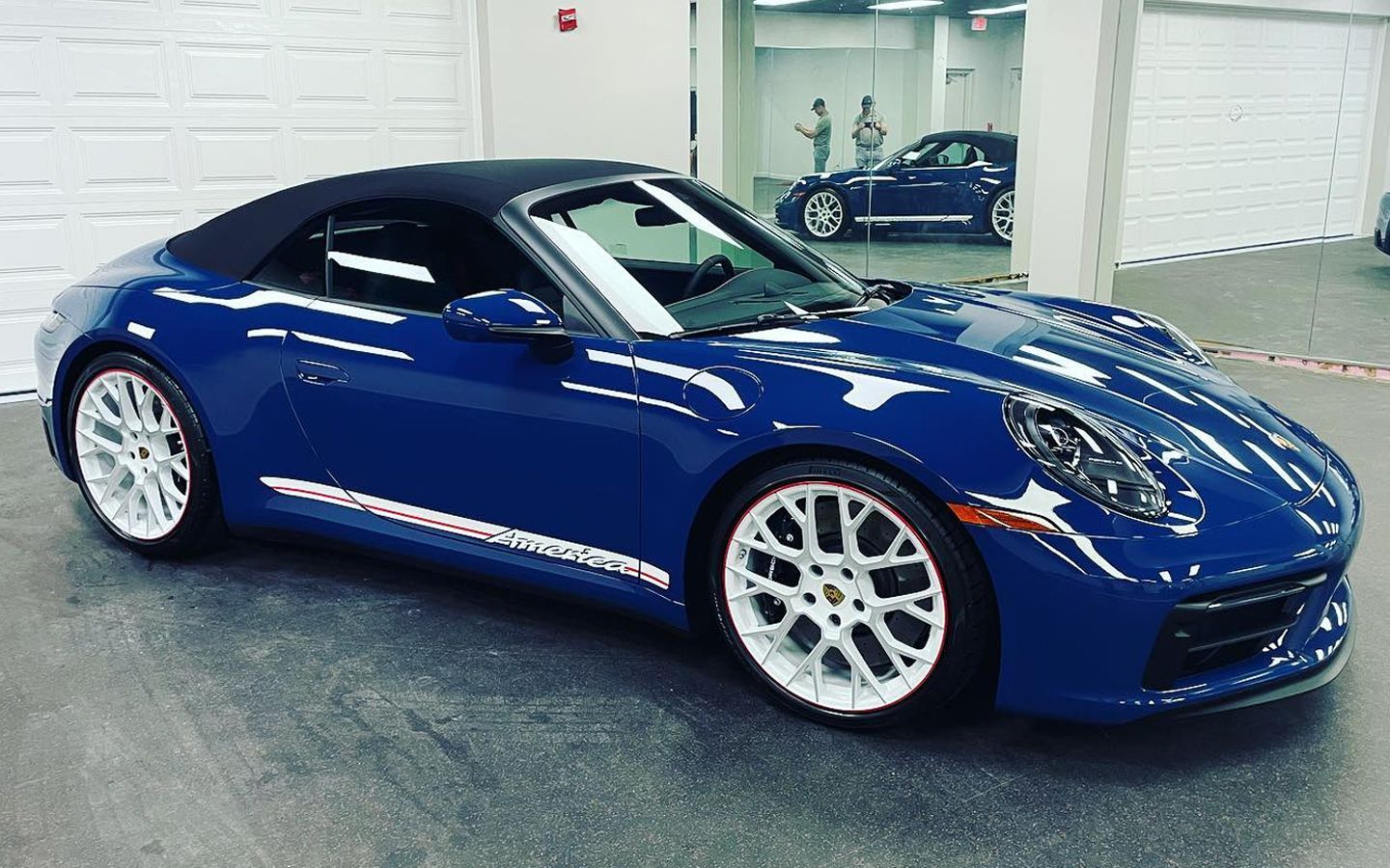Blue Porsche 911 Carrera GTS Cabriolet America Edition with white wheels.
