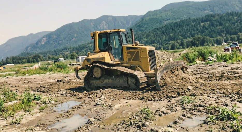 A bulldozer leveling dirt to prepare a site for a new building.
