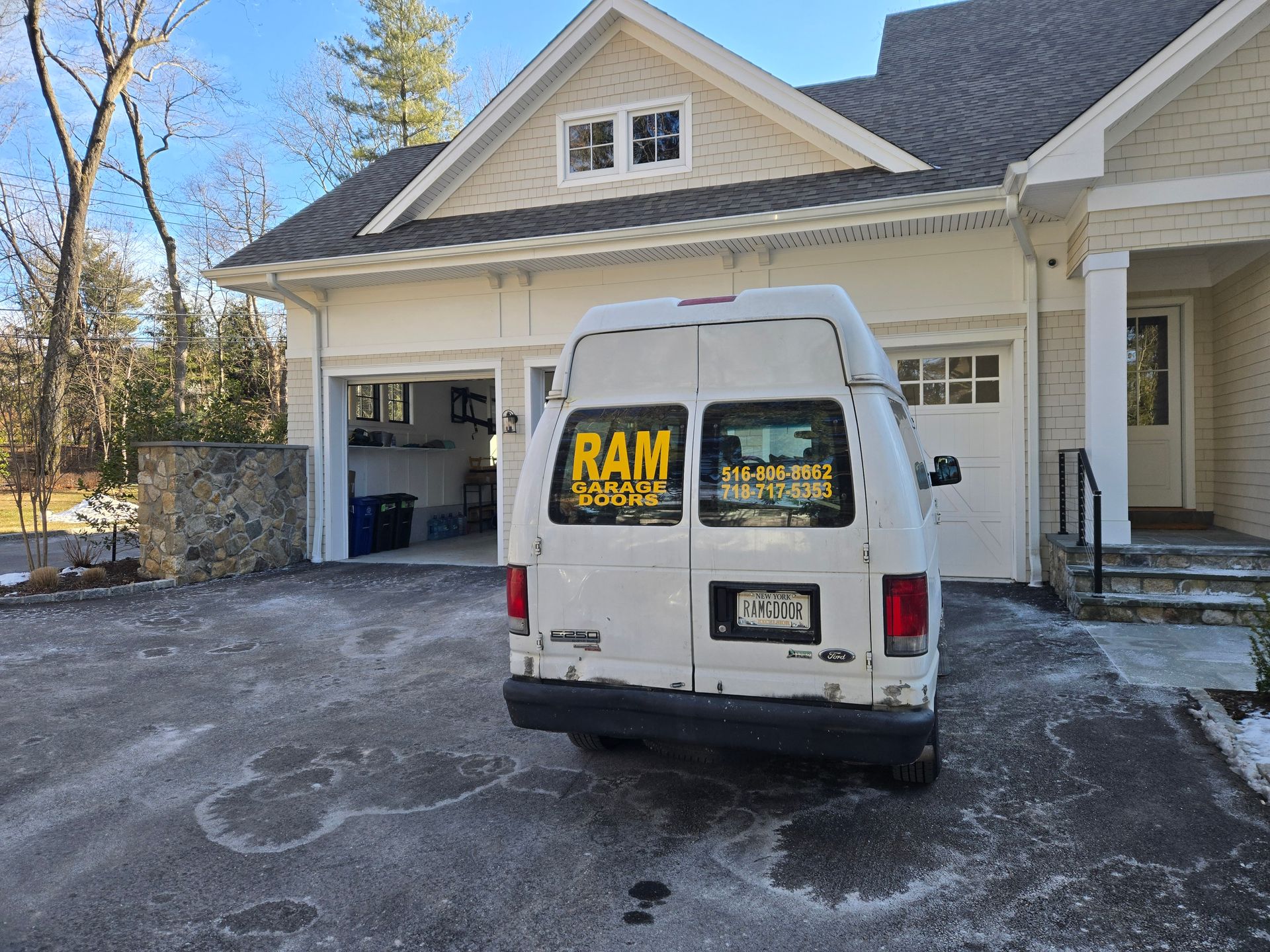 White van parked in front of a house with an open garage. 