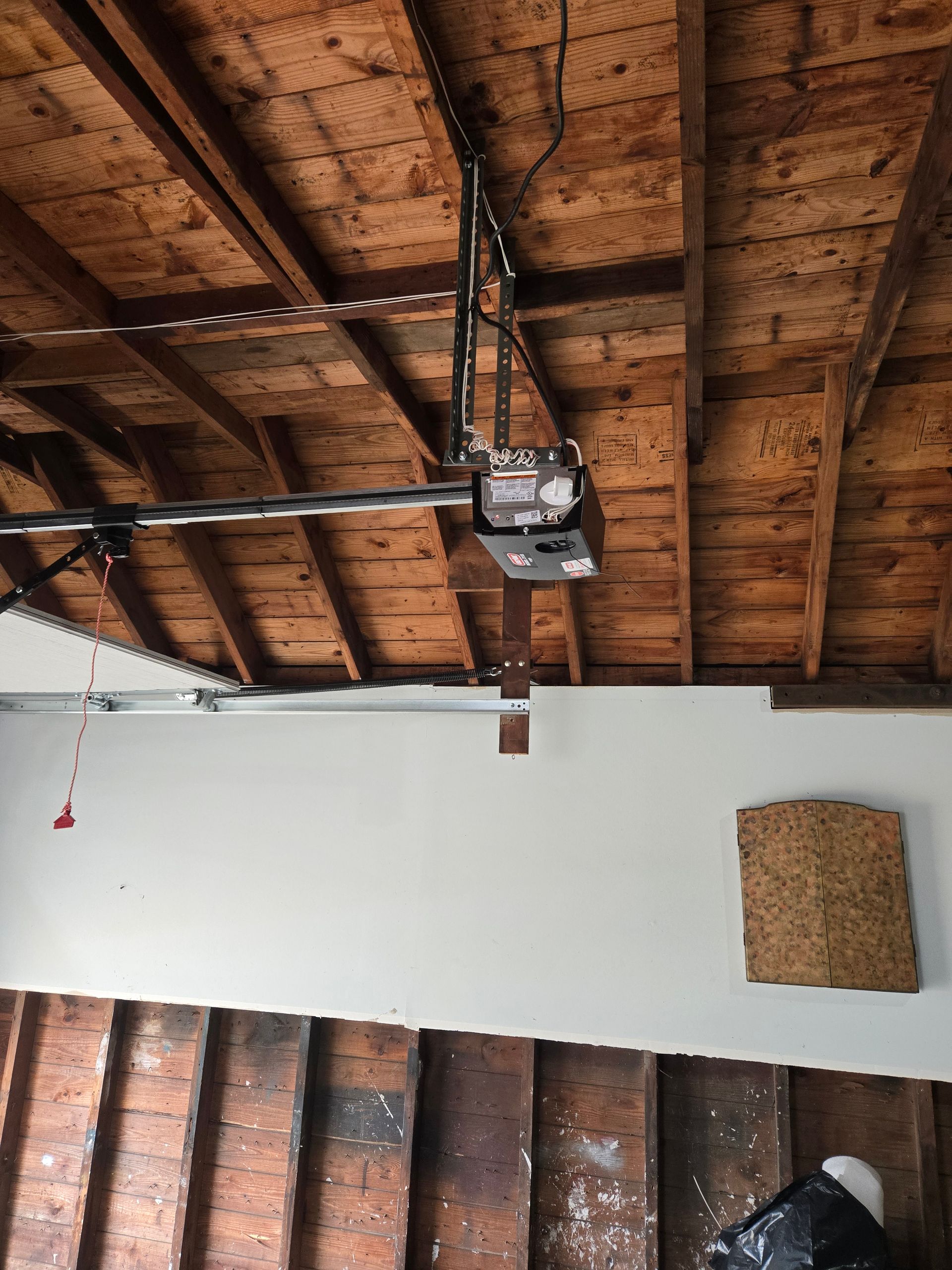 Garage ceiling with a garage door opener attached. The walls are partially covered in white paint.