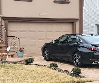A black car is parked in front of a garage door.